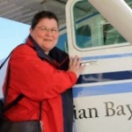 Women with red jacket next to a door of a small plane