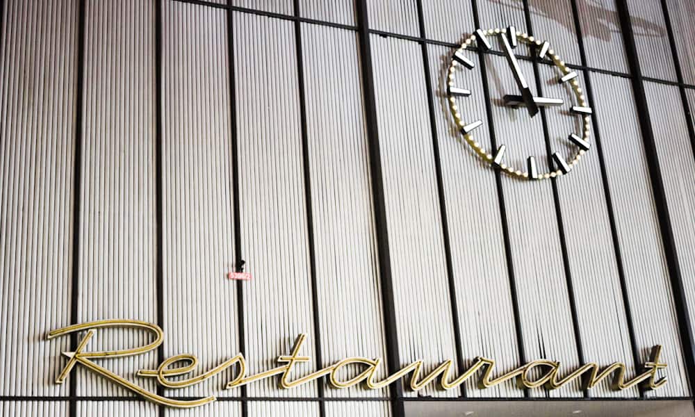 sign of restaurant and a clock on a grey wall