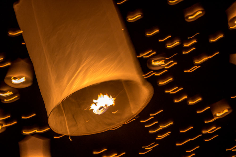 Papierlaternen leuchten am schwarzen Nachthimmel beim Yee Peng Festival in Thailand