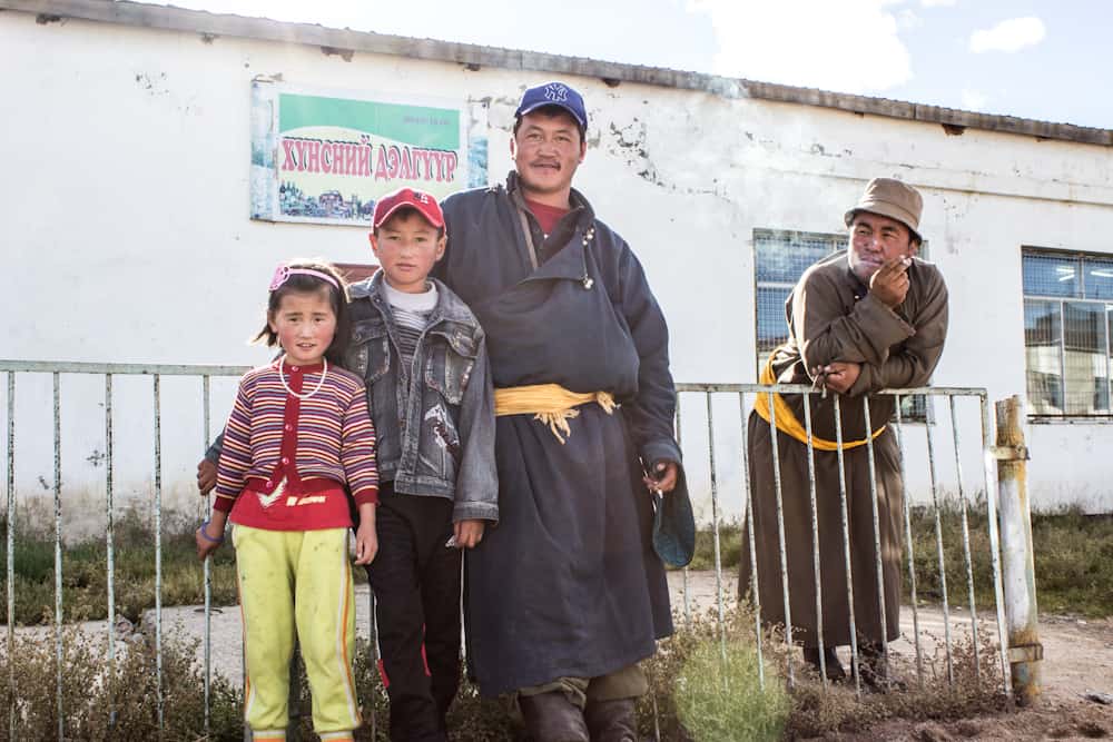 family smiling at the camera while a man smokes a cigarette next to them