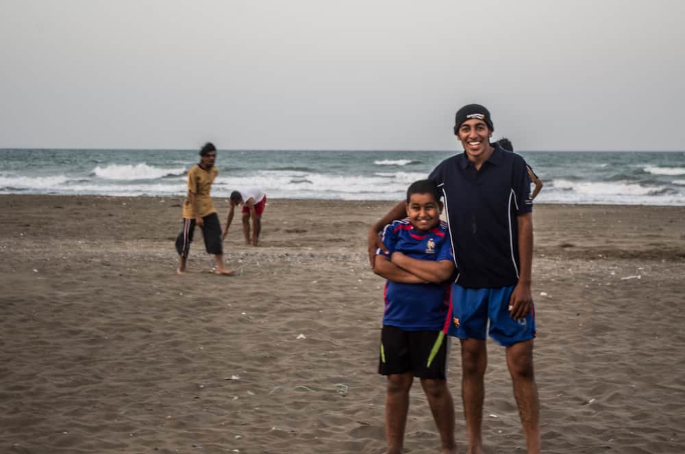 family smiles on a beach in Oman wearing athletic clothing 