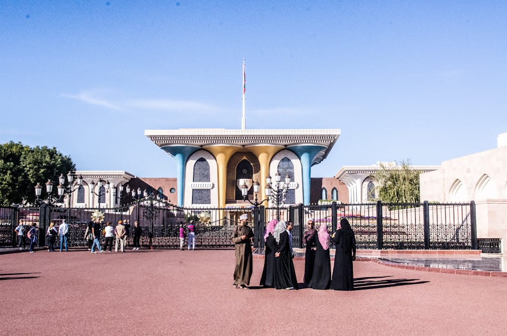 women talking in a town square with gold and blue building behind them