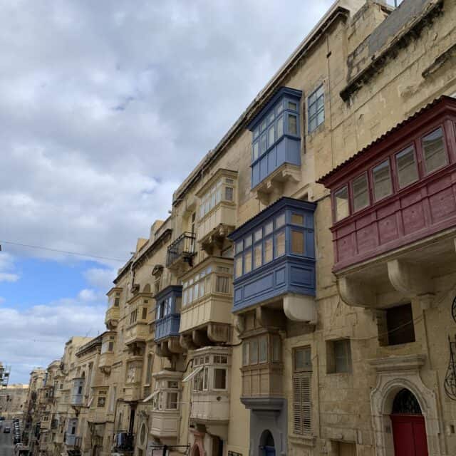 Colorful wooden Malta Balconies line a busy street of stone buildings