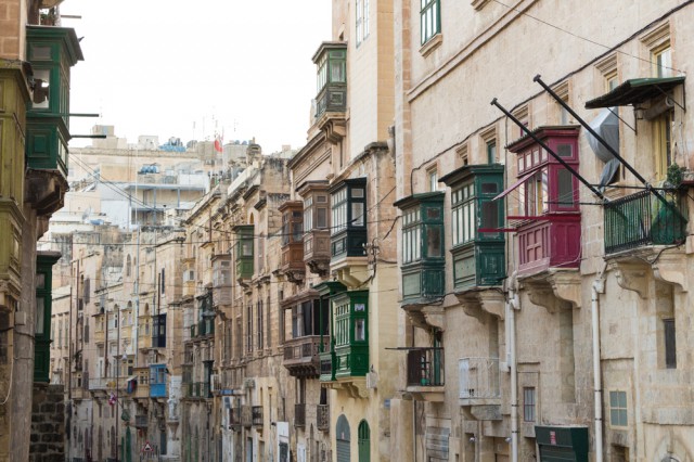 Colorful wooden balconies in red, green and brown line a street of stone buildings