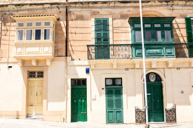 Bunte Malta-Balkone in Grün säumen eine Steinstraße in Valletta