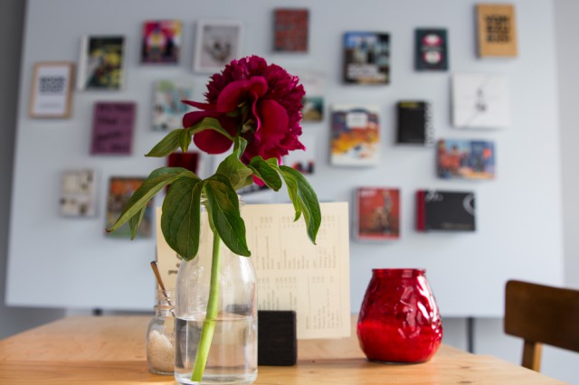 Red flower in a glass jar on a cafe table