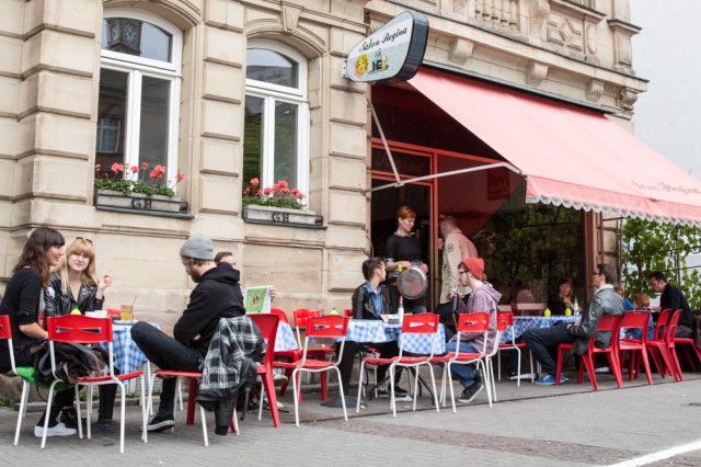 people sitting on red chairs outside a cafe