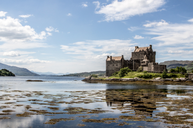 Eilean Donan Castle reflected in the water with a beautiful blue sky
