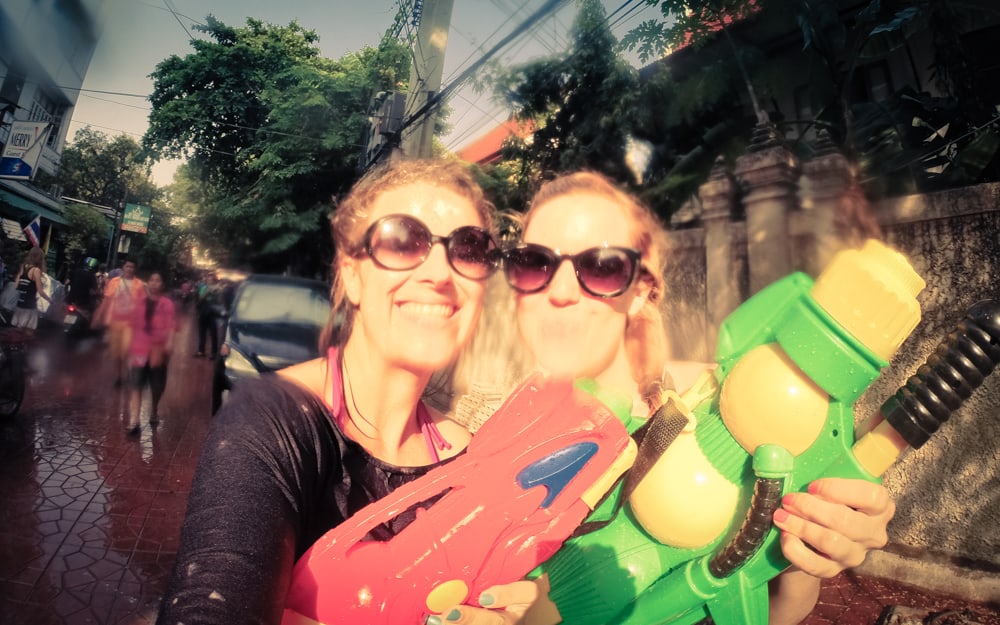 two women with sunglasses and red and green water guns