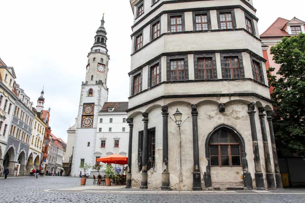 Görlitz Townsquare with a large clock tower made of white stone and a old cafe of stone