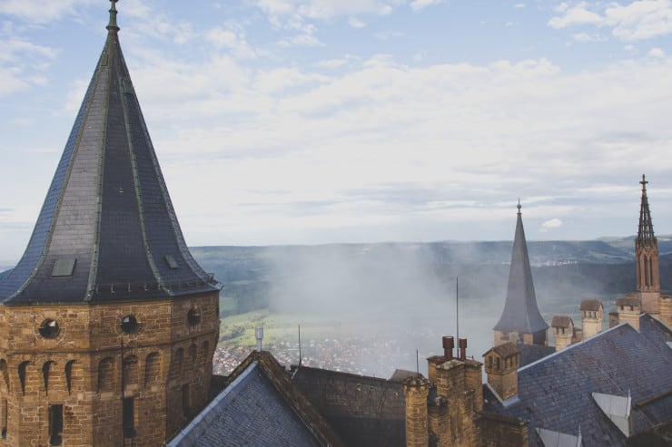 castle towers with pointed spires with a low cloud covering the landscape in the background