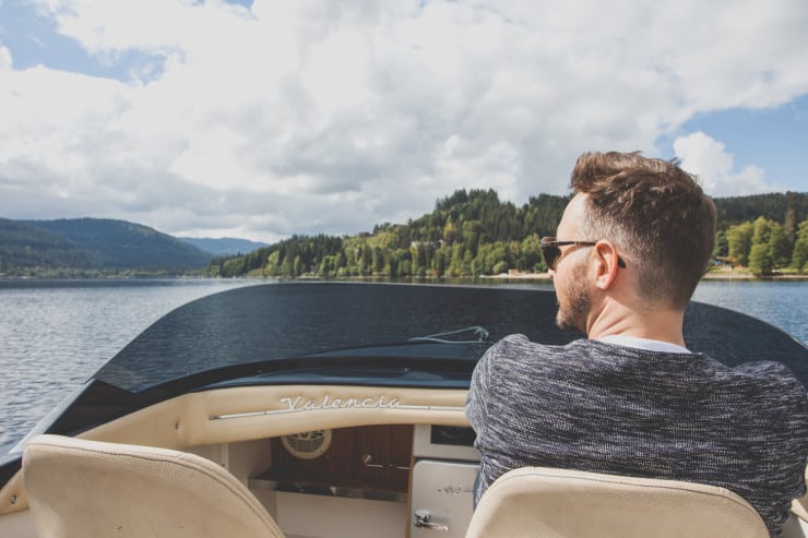 man smiles in a boat touring around a lake 