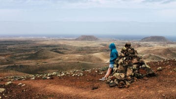 Wanderer blickt ueber Vulkanlandschaft auf Fuerteventura