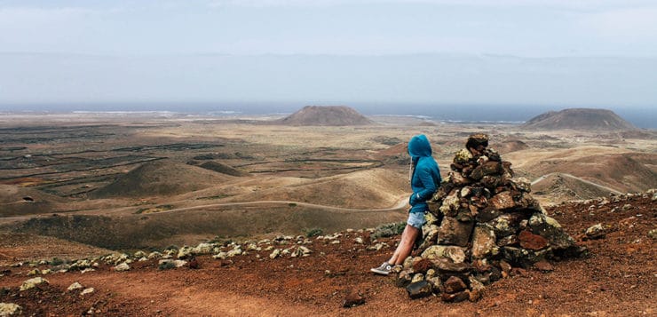 Wanderer blickt ueber Vulkanlandschaft auf Fuerteventura