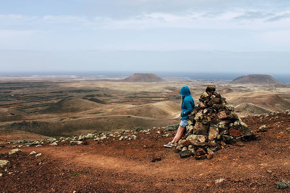 Wanderer blickt ueber Vulkanlandschaft auf Fuerteventura