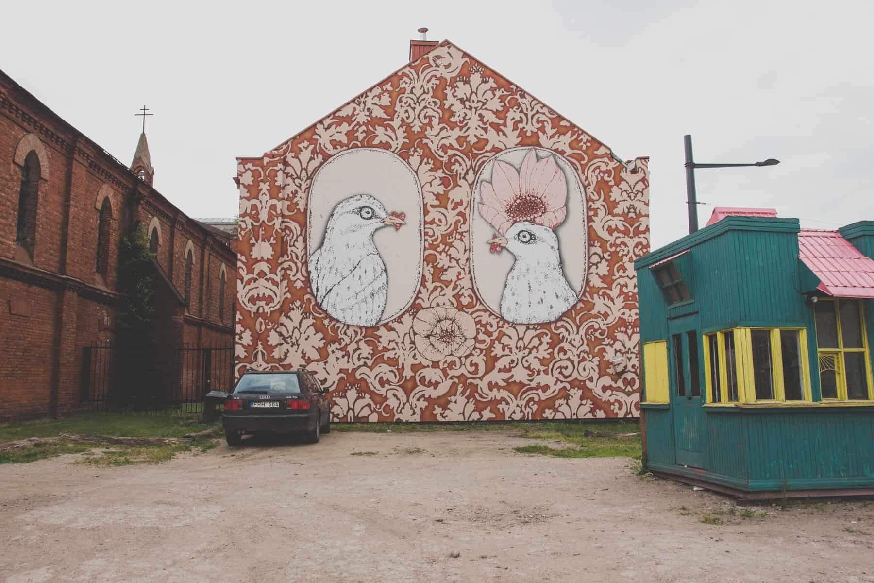 Zwei Vögel mit Herzen und Blumen auf der Seite eines Gebäudes gemalt