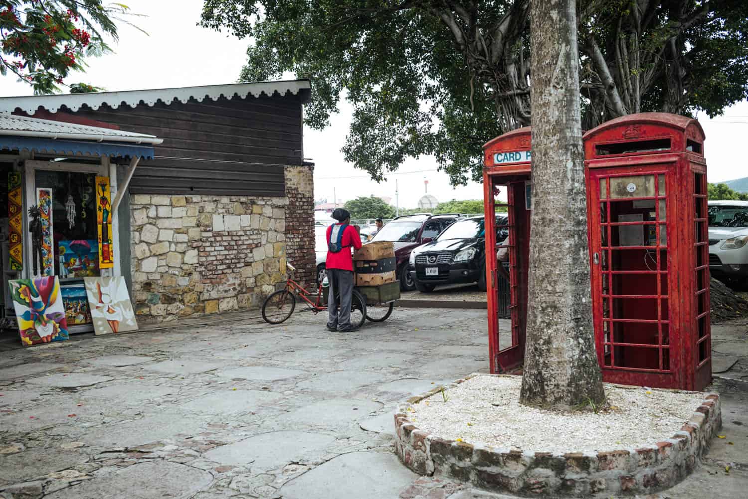 kleiner Markt mit einem Mann, der Dinge auf einem Fahrrad transportiert, und zwei Telefonzellen