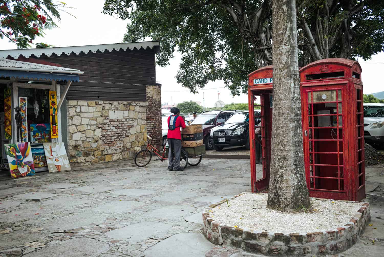 small market with a man transporting things on a bike and two phone booths