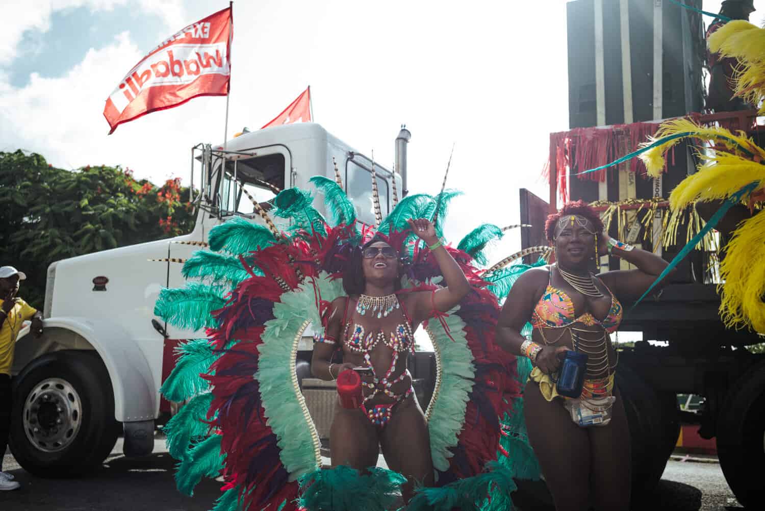 smiling women colorful feathered costume with her hands up in the air in celebration