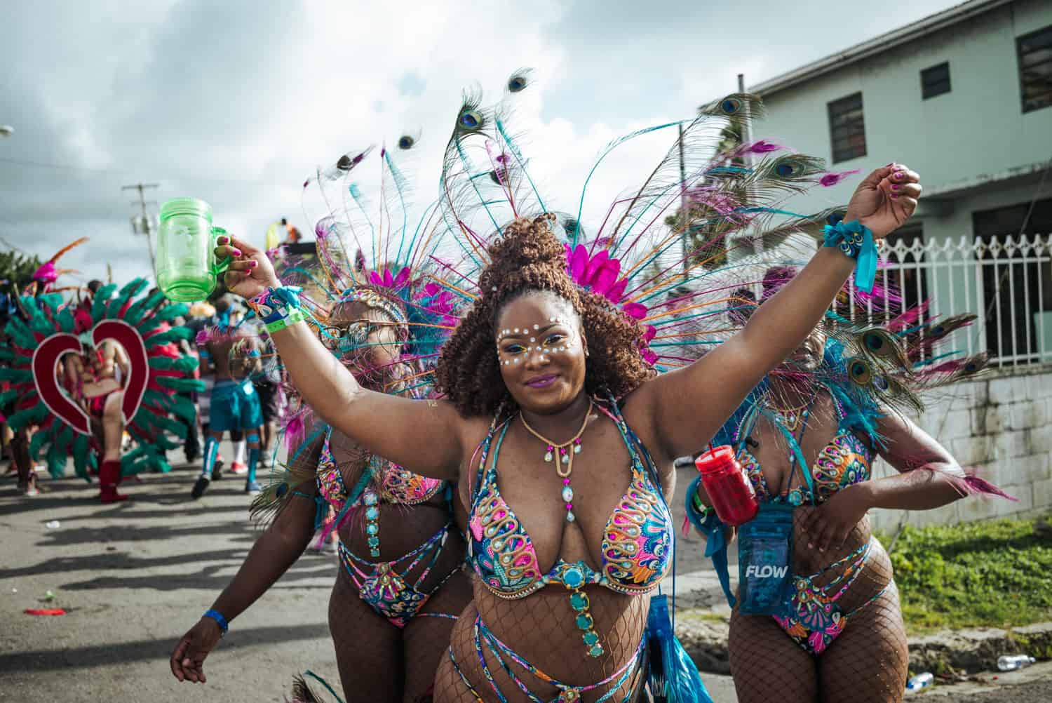 Bunte Frauen in Karnevalskostümen lächeln mit ihren Freunden hinter ihr