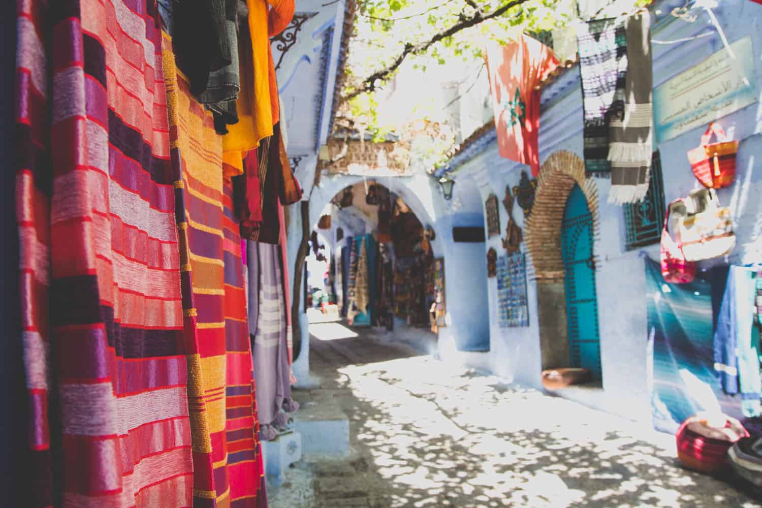 Bunte Kleidung hängt an der Seite einer von blauen Gebäuden gesäumten Straße