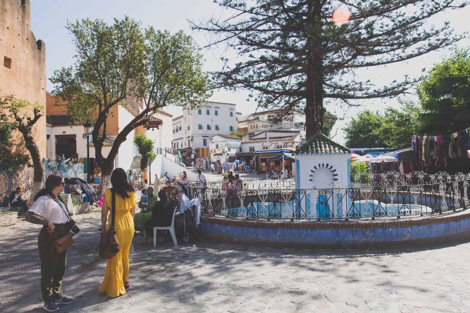 Stadtplatz mit großem Brunnen und vielen Menschen, die das sonnige Wetter genießen