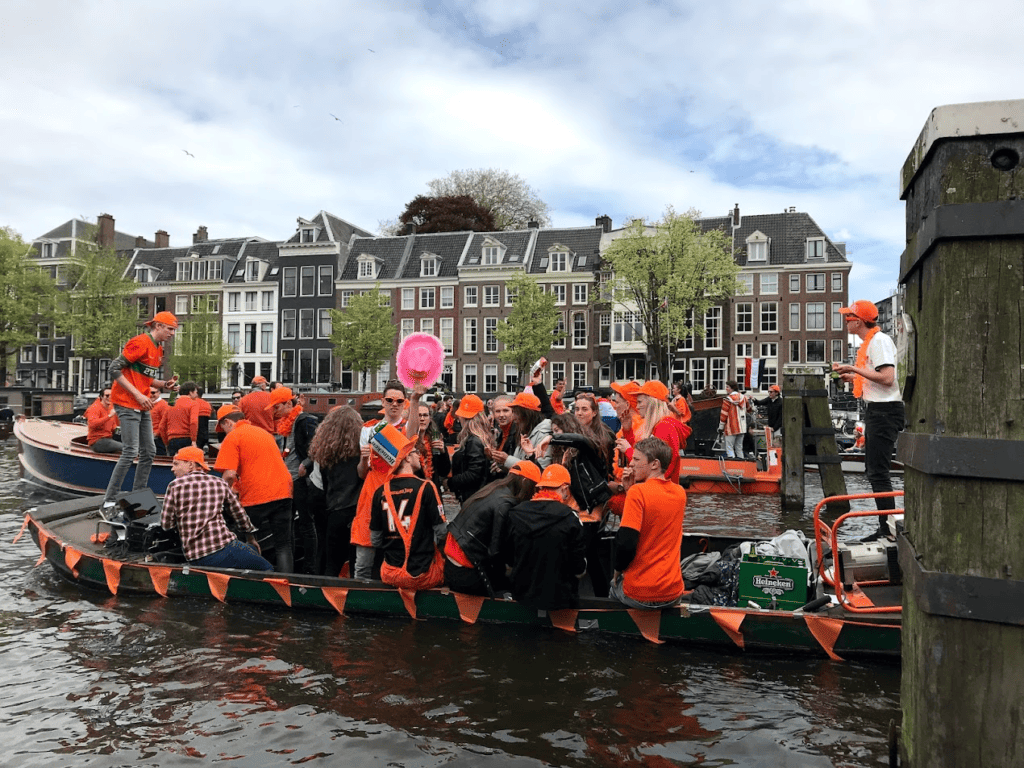 Several Boats of people wearing orange and partying on King's Day in Amsterdam