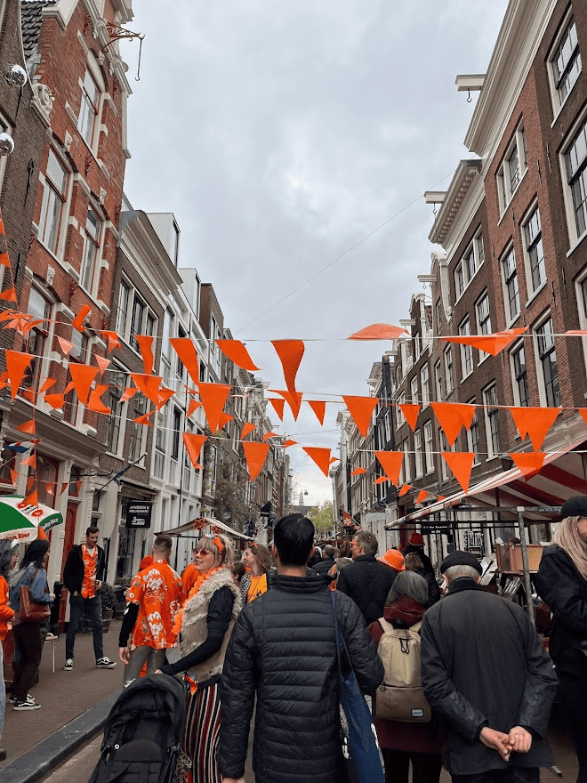Man walking down crowded street with Orange Party Decorations in Amsterdam on King's Day