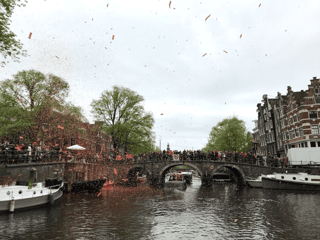 Orange Confetti exploding over canal houses and bridge in Amsterdam