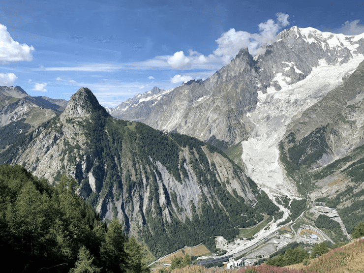 Snow covered Alps Mountain Range on The Tour du Mont Blanc Trail with blue sky and pine trees