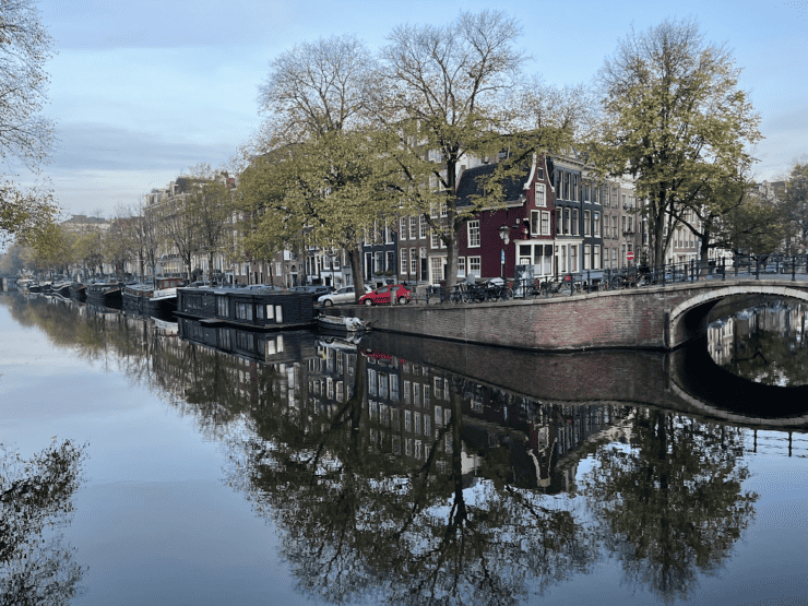 Amsterdam canal houses reflected in the water of a canal with autumn trees