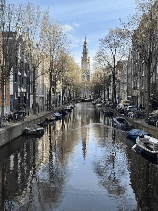 Old Clock Tower and canal houses reflected on water in Amsterdam, an beautiful thing to see moving to another country