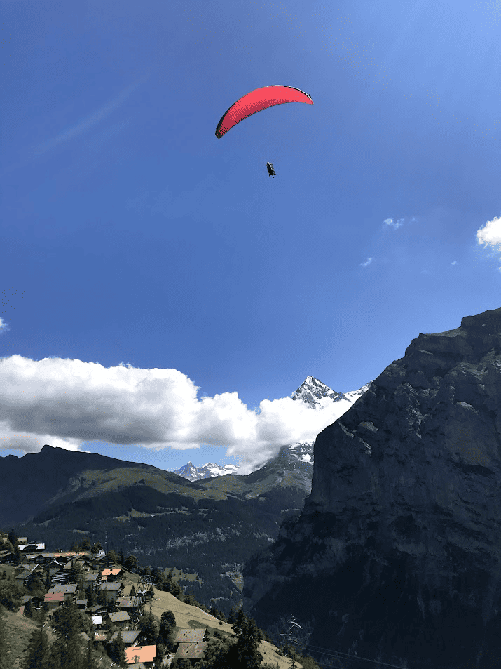 red parachute shown paragliding Switzerland over the Alps