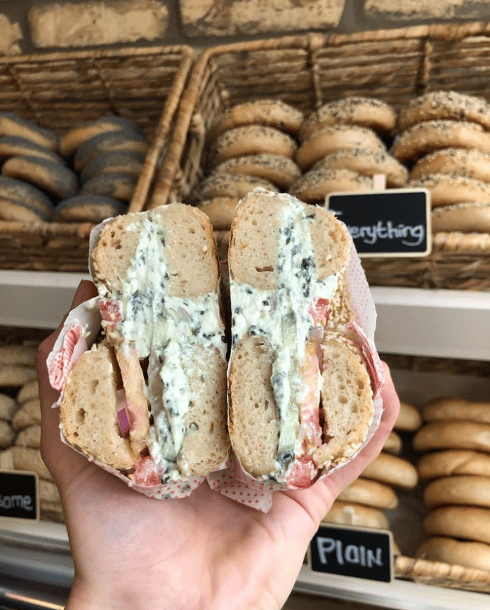 Bagel with Cream cheese and ham held in Hand at Flo's Appetizing Brunch Amsterdam