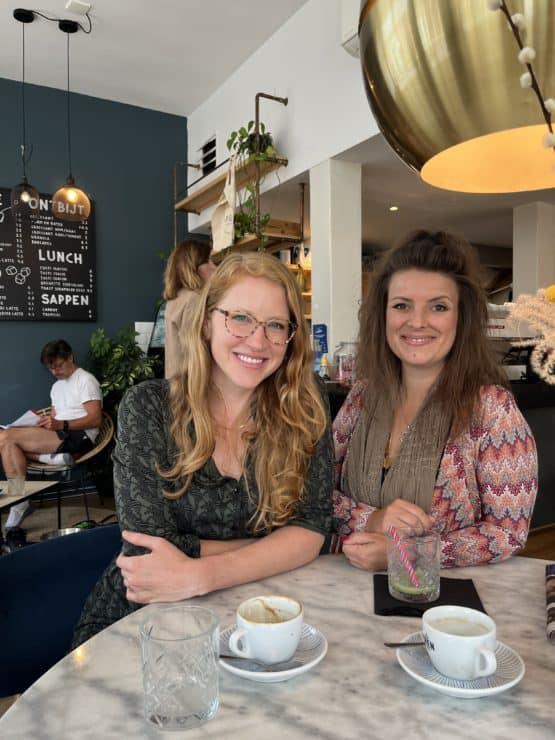 two women smiling in a cafe with empty coffee cups