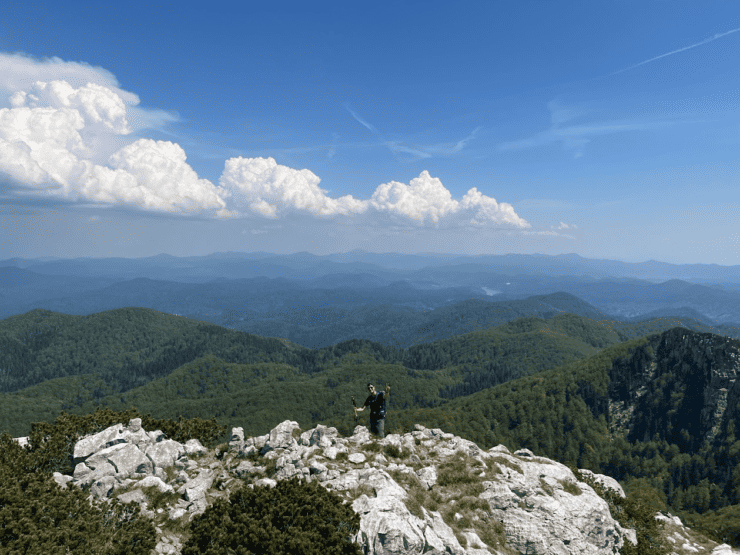 man smiling hiking over green mountain range on a Croatia Roadtrip