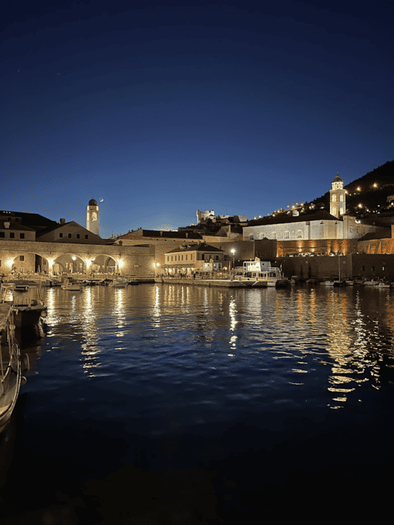 Dubrovnik at night - white stone building reflecting on the water in a harbor
