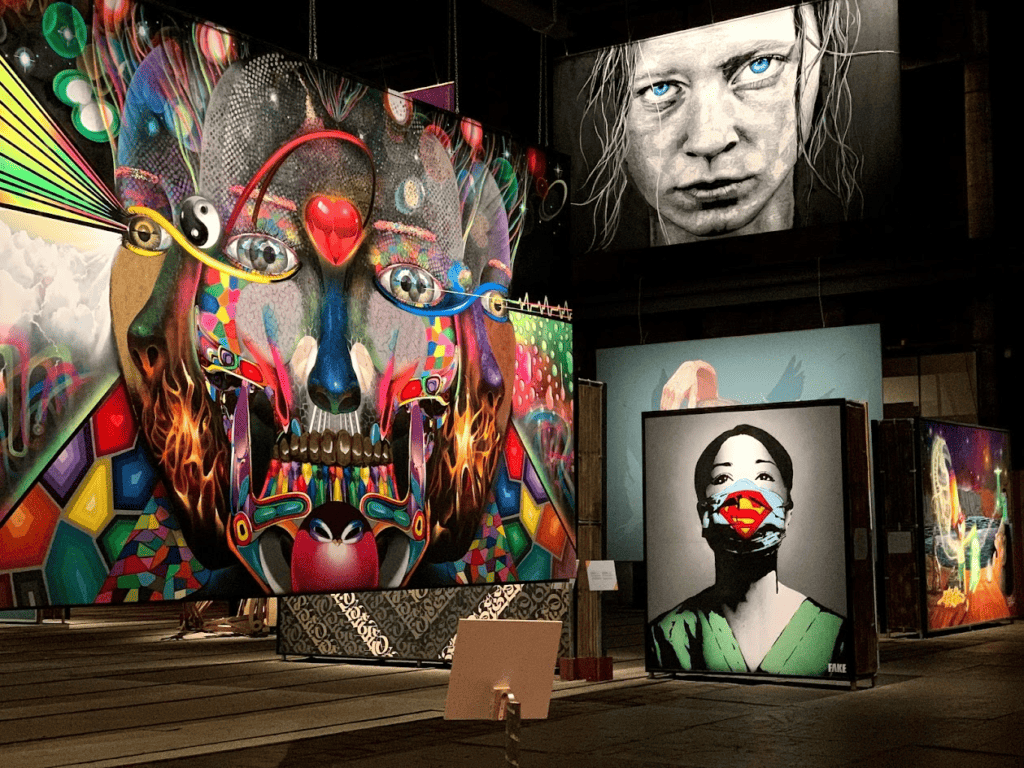Large billboard size Street art murals of various colors all with faces, one abstract, one nurse and one with intensely blue eye