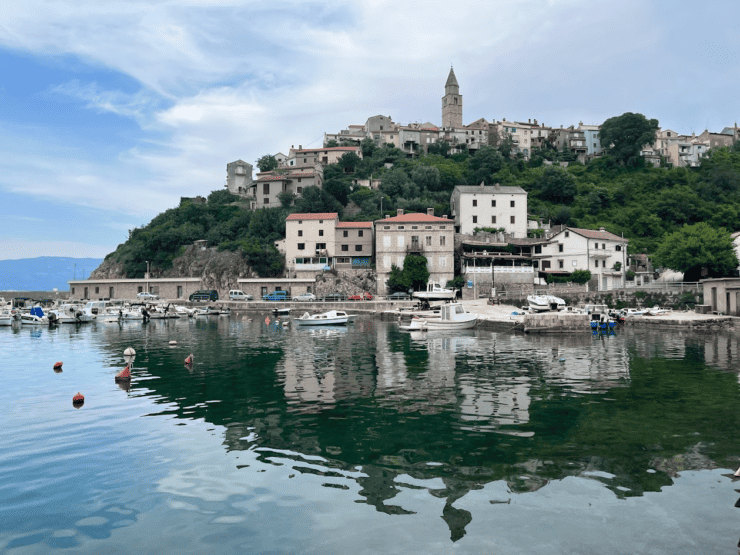 Vrbnik town reflected over water with small boats a stop on croatia vacation