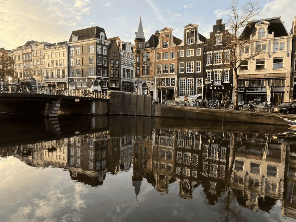 Alte Kanalhäuser und eine Brücke spiegeln sich über dem Wasser in Amsterdam