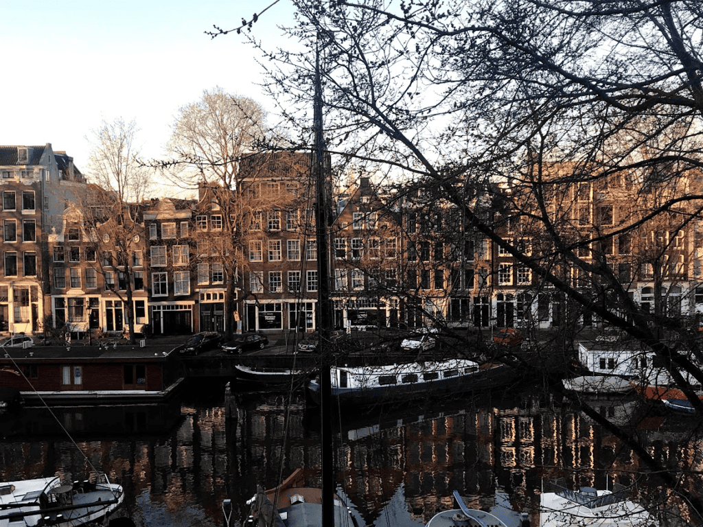 Alte Kanalhäuser und eine Brücke spiegeln sich über dem Wasser ein Amsterdam Sehenswürdigkeiten