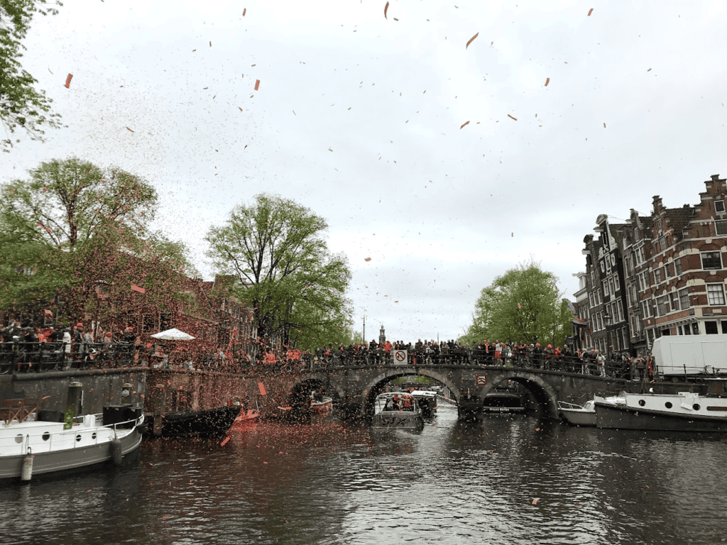 Orangefarbenes Konfetti über einem Kanal in Amsterdam
