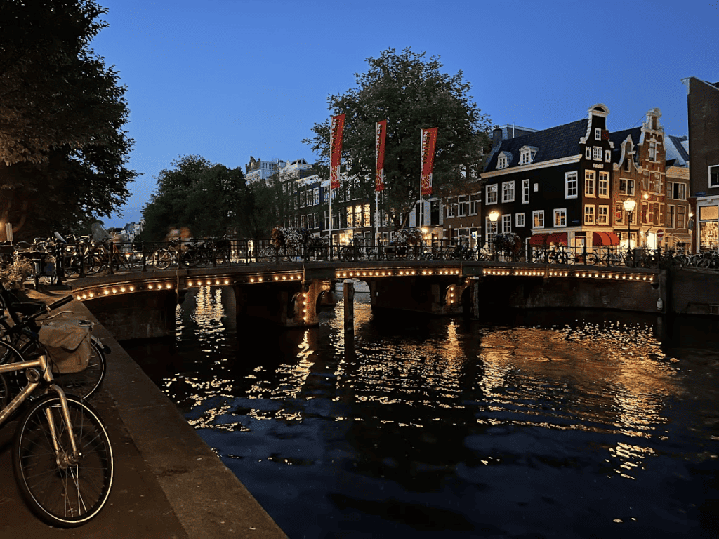 Alte Kanalhäuser und eine Brücke spiegeln sich über dem Wasser in Amsterdam