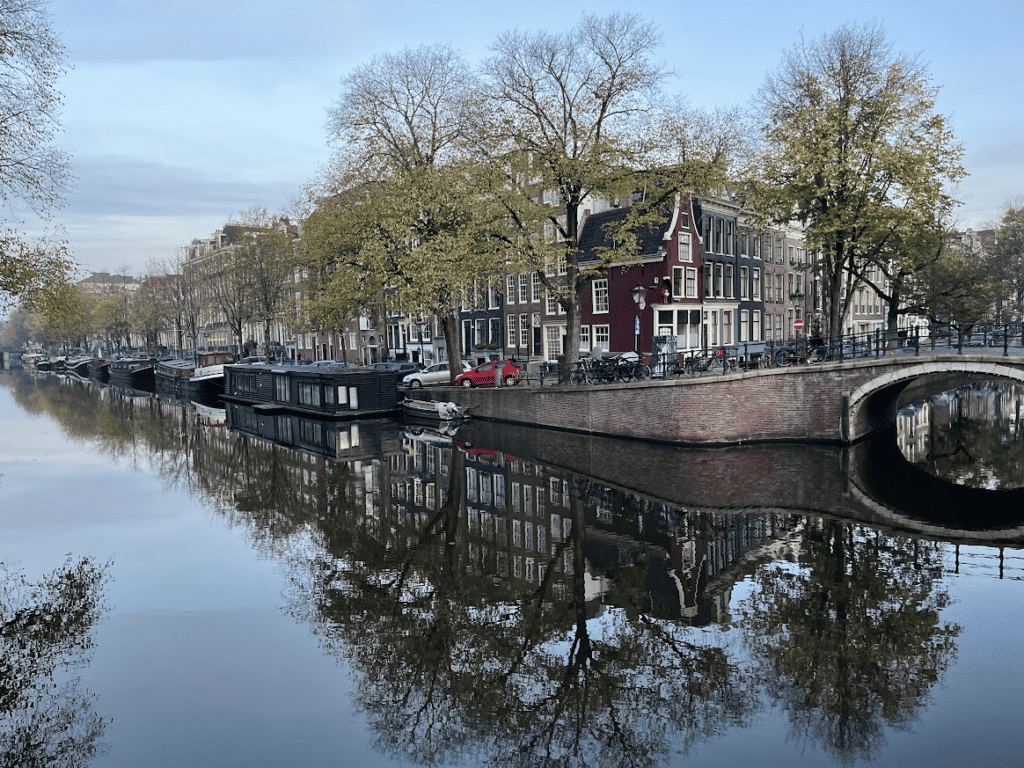 Alte Kanalhäuser und eine Brücke spiegeln sich über dem Wasser in Amsterdam