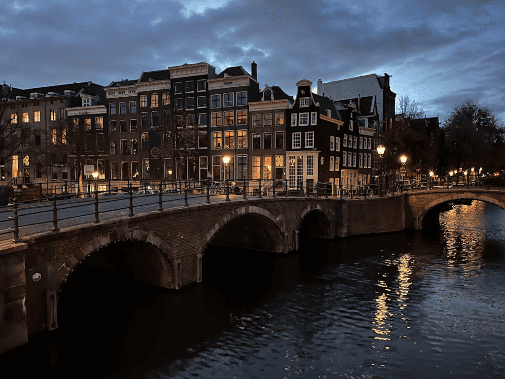 Alte Kanalhäuser und eine Brücke spiegeln sich über dem Wasser in Amsterdam