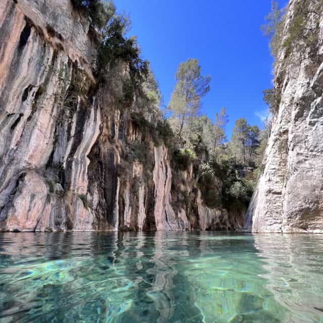 Canyon surrounding crystal waters of the thermal baths of Montanejos with blue sky