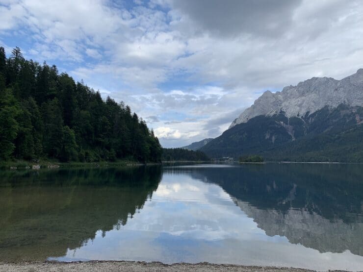mountain range reflection across a lake with pine trees