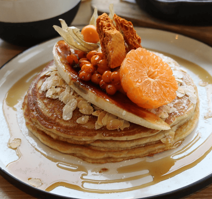 Stack of Pancakes with caramelized banana and orange wedge for a vegan brunch in Amsterdam at Dignita