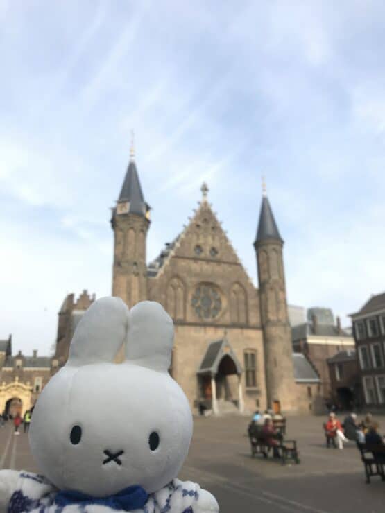 Miffy (stuffed animal) with an old church in the background touring around Amsterdam with kids