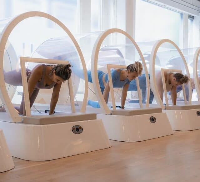 3 women shown in glass pods doing Pilates moves